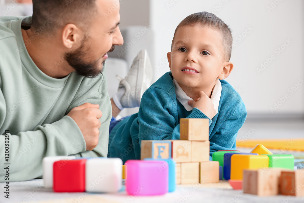 Happy father and his little son playing with colorful cubes on floor at home Happy father and his little son playing with colorful cubes on floor at home