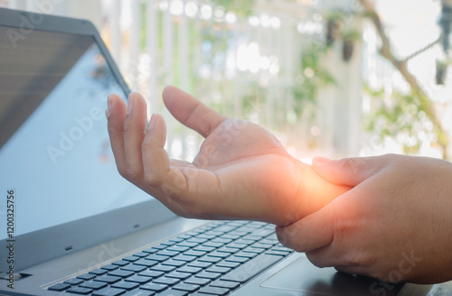 Young man working in a home office with carpal tunnel syndrome or wrist joint inflammation, massage on the hand and arm for relief pain from hard work for stiff, cramp symptom, carpal tunnel syndrome.