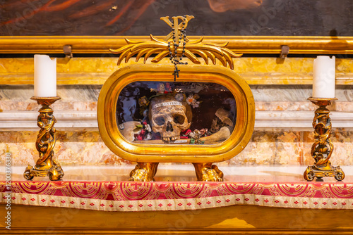 Fotografi The remains of Saint Valentine are displayed in a glass relic at Basilica of Santa Maria in Cosmedin in Rome, surrounded by decorative candles and ornate furnishings, reflecting a sacred atmosphere