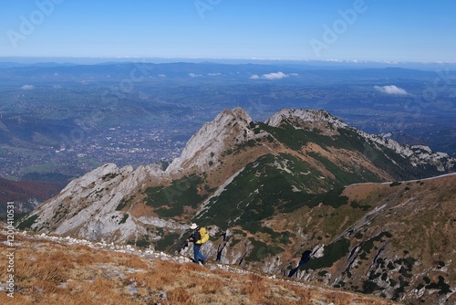 Scenery of autumn Tatras Mountains with silhouettes of hiking people. Giewont Peak on background. Czerwone Wierchy range from around Kasprowy Wierch Peak, Tatras Mountains, Poland.  