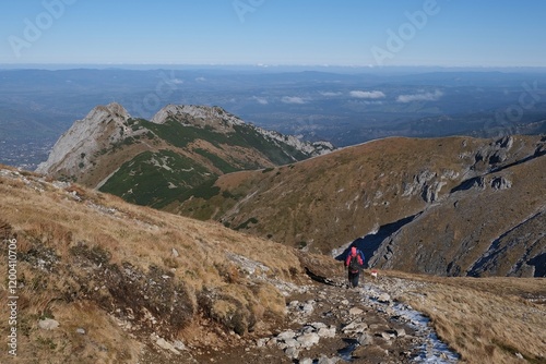 Scenery of autumn Tatras Mountains with silhouettes of hiking people. Giewont Peak on background. Czerwone Wierchy range from around Kasprowy Wierch Peak, Tatras Mountains, Poland.  