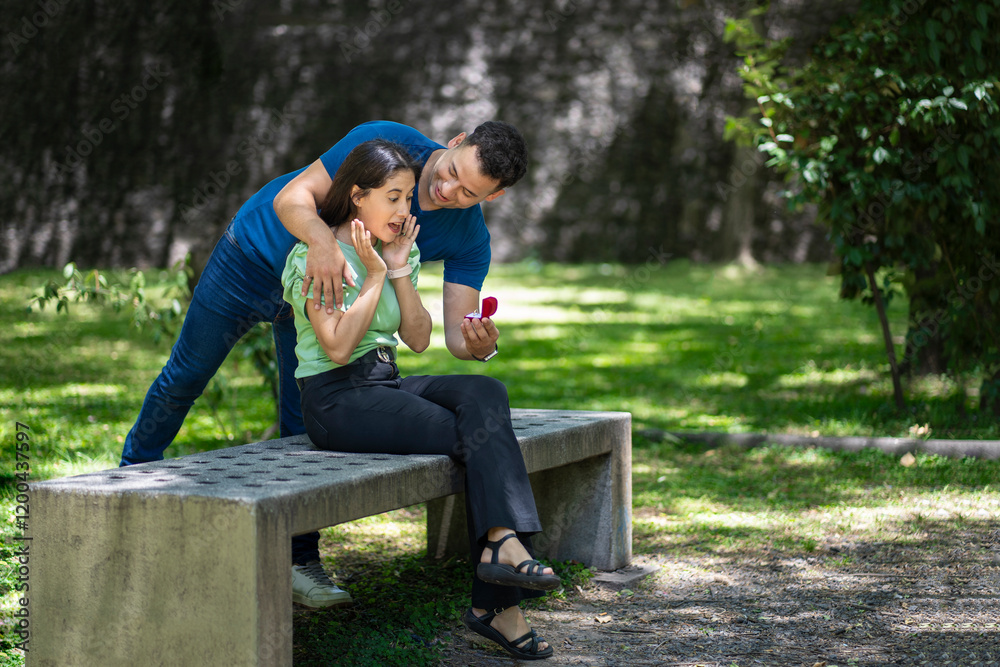 Fototapeta premium Young man surprising his girlfriend in a park with a wedding ring
