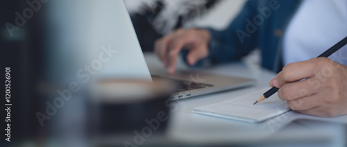 Close up, business woman hand writing on notepad, working on laptop computer at coffee shop. Woman planning work project. Student online study and taking note, e-learning concept