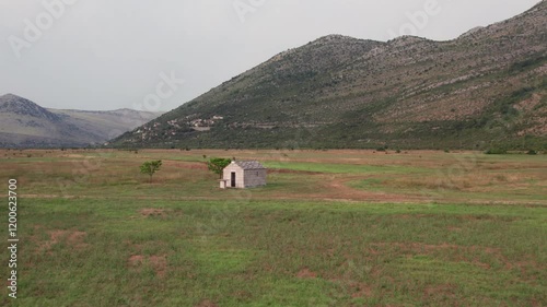 Aerial view of small stone chapel in a field surrounded by mountains. Ravno, Bosnia and Herzegovina photo