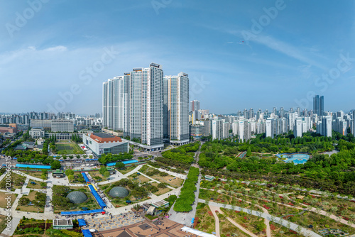 Jung-dong, Bucheon-si, Gyeonggi-do, South Korea - May 4, 2024: Aerial and spring view of walking trail and trees against Bucheon City Hall and apartments at Bucheon Central Park photo