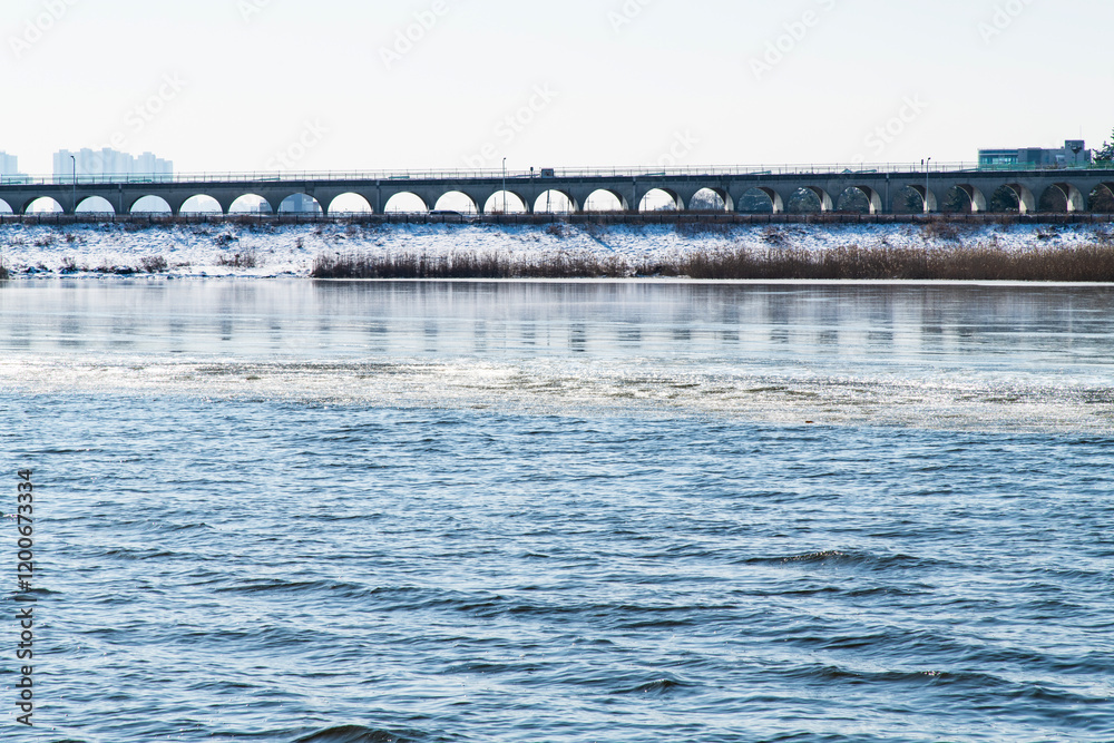 frozen river with snow-covered riverbank and bridge