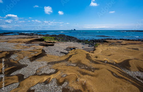 Spring view of sands and volcanic rocks at low tide against Brother Islands and sea horizon at Sagye Beach of Seogwipo-si, Jeju-do, South Korea photo