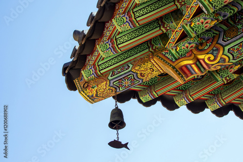 Hapcheon-gun, Gyeongsangnam-do, South Korea - March 10, 2024: Low angle view of wind chime on the eaves of Buddhist sanctuary against blue sky at Haeinsa Temple photo