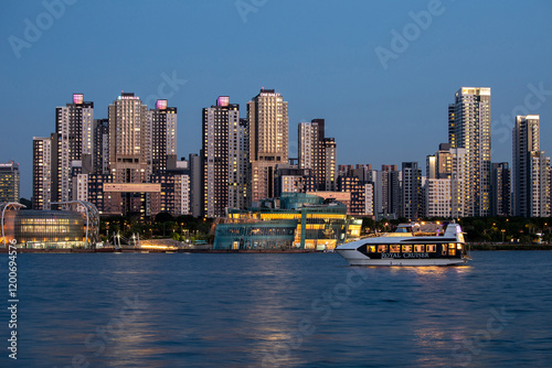 Banpo, Seocho-gu, Seoul, South Korea - May 8, 2024: Sunset and night view of a cruise ship sailing on Han River against Sevit Floating Island and apartments photo