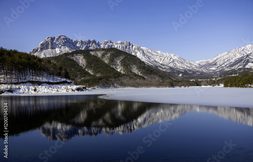 Winter and morning view of water and melting ice on Wonam Reservoir against snow covered Ulsanbawi Rock at Wonam-ri of Gosung-gun, Gangwon-do, South Korea photo