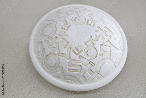 Sangju-si, Gyeongsangbuk-do, South Korea - April 22, 2024: Close up of a white convex ceramic dish with pattern of korean consonant characters on floor of Sangju pottery photo