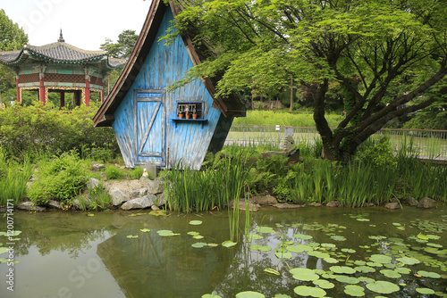 Neung-dong, Gwangjin-gu, Seoul, South Korea - May 24, 2024: Summer view of a blue wood hut with tree and aquatic plants on Hwangyeong Pond at Children's Grand Park photo