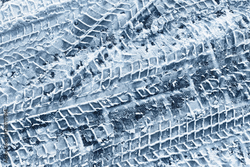 Snow tyre mark. Asphalt covered in snow. Winter road background. Car imprint on frozen ground. Tire trail on ice. City streets covered in snow during heavy snow fall.	