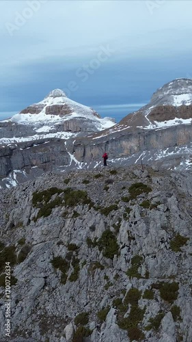 A person stands on a rocky viewpoint with snowy peaks, near Punta de la Espata, Spain photo