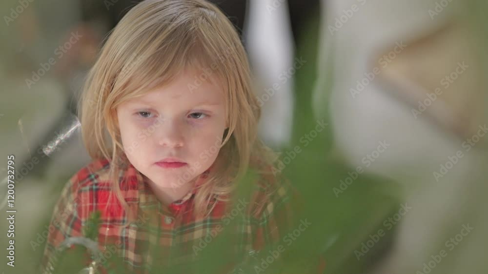 Cute blonde little girl looking with illusion at the christmas tree Cute blonde little girl looking with illusion at the christmas tree