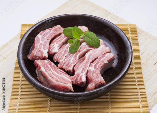 Close up of raw Pork back rib flesh and bone with green herb leaf on jar and sushi roller mat, South Korea photo