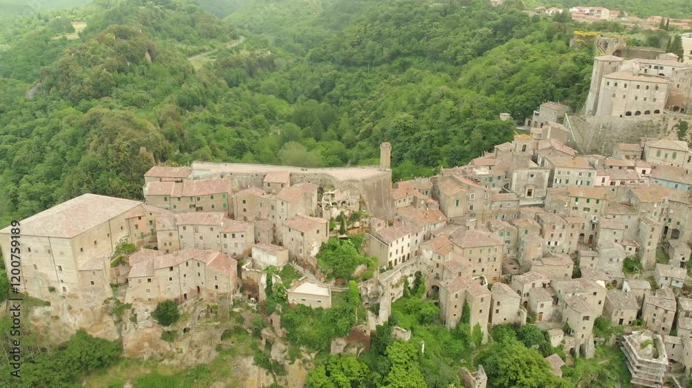 Aerial summer afternoon view of Sorano. Rooftops of an ancient medieval hill town hanging from a tuff stone over the Lente River. Etruscan heritage. Province Grosseto, Tuscany, Italy. Aerial summer afternoon view of Sorano. Rooftops of an ancient medieval hill town hanging from a tuff stone over the Lente River. Etruscan heritage. Province Grosseto, Tuscany, Italy.