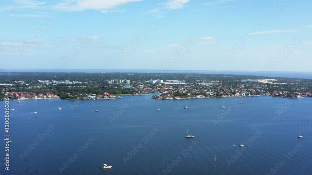 A drone fly-in showcasing the tranquil waters, moored sailboats, and charming waterfront communities of Boca Ciega Bay in St. Petersburg, Florida. A drone fly-in showcasing the tranquil waters, moored sailboats, and charming waterfront communities of Boca Ciega Bay in St. Petersburg, Florida.