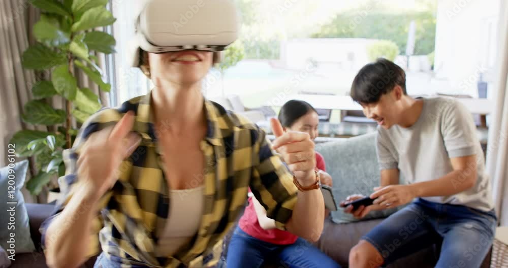 Using VR headset, woman enjoying virtual reality while family recording with smartphones