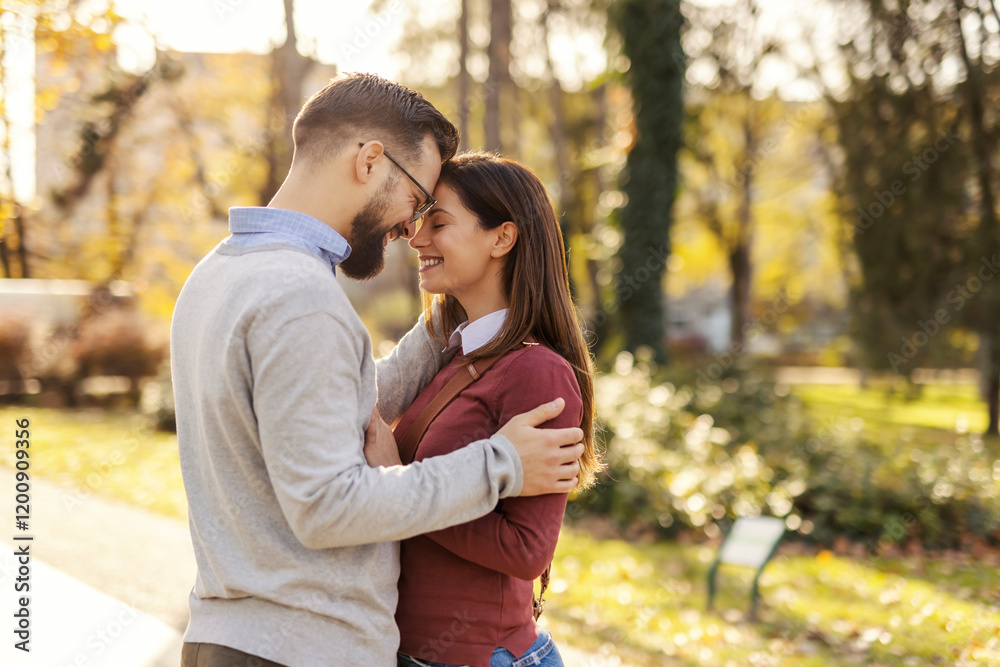 Side view of young romantic couple cuddling and hugging in city park. Side view of young romantic couple cuddling and hugging in city park.