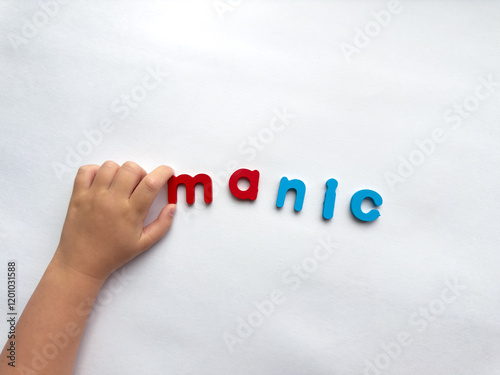 Childs hand arranging colorful letter manic letters on white background