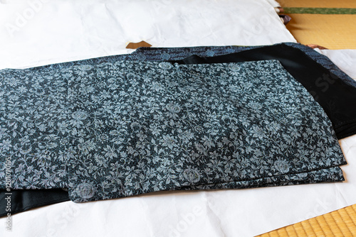 畳の上に複数枚の重ねた青色と黒色の着物
