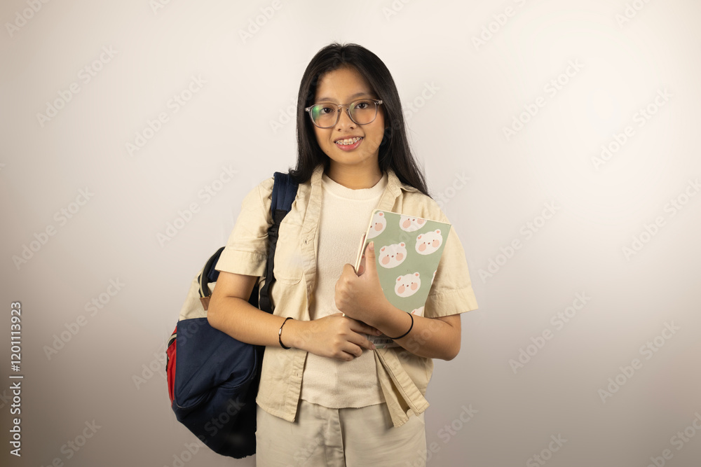 A student holding a not book and bringing a back pack A student holding a not book and bringing a back pack