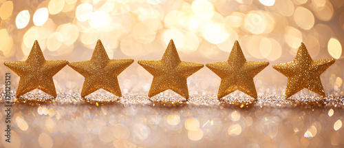 Five golden stars are arranged in a row against a shimmering, blurred background, creating a festive and celebratory mood.