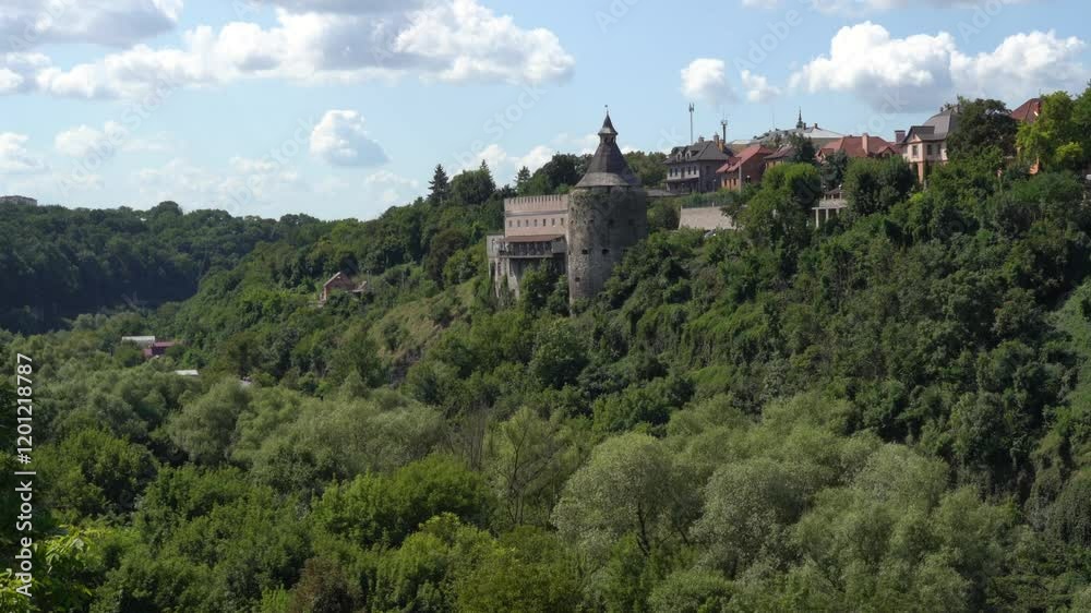 Ukraine,Kamianets Podilskyi,Honcharska Bashta tower surrounded by greenery on a sunny day with white clouds.Pan right. Ukraine,Kamianets Podilskyi,Honcharska Bashta tower surrounded by greenery on a sunny day with white clouds.Pan right.