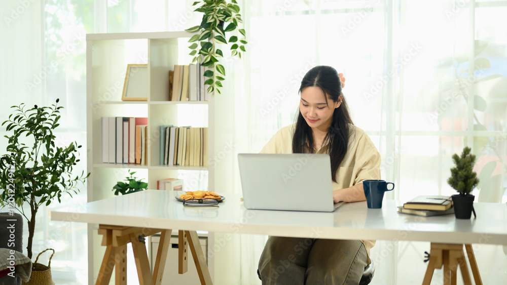 Focused young asian woman working in a bright home office Focused young asian woman working in a bright home office