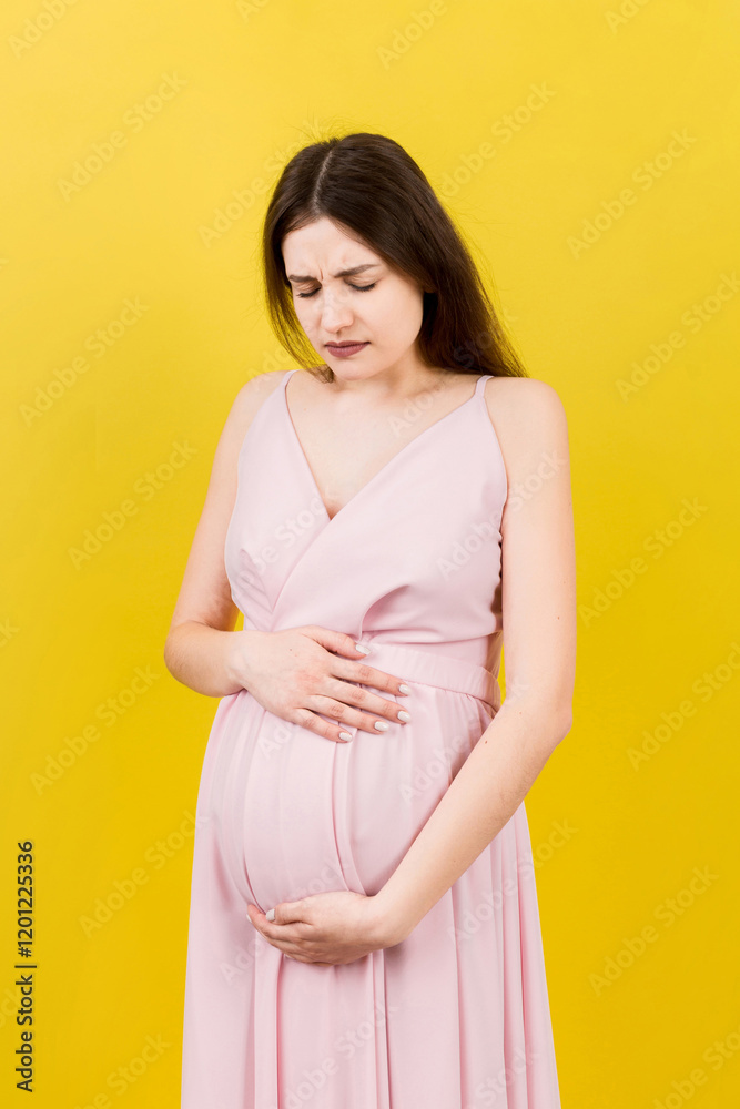 a pregnant girl who has a stomach ache stands on a colored background. isolated a pregnant girl who has a stomach ache stands on a colored background. isolated
