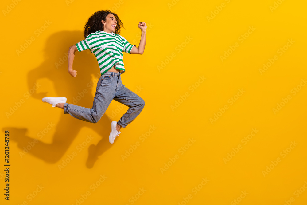 Full size profile photo of pretty young girl jump run empty space wear striped t-shirt isolated on yellow color background Full size profile photo of pretty young girl jump run empty space wear striped t-shirt isolated on yellow color background