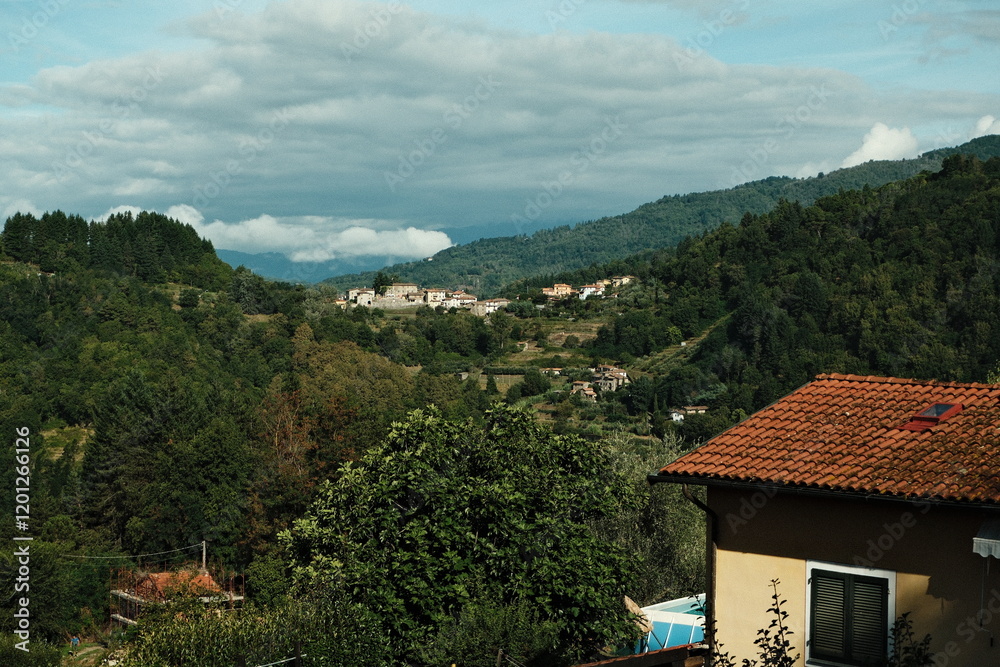 Scenic view of a tranquil mountain village surrounded by lush greenery in the Italian countryside during daytime Scenic view of a tranquil mountain village surrounded by lush greenery in the Italian countryside during daytime