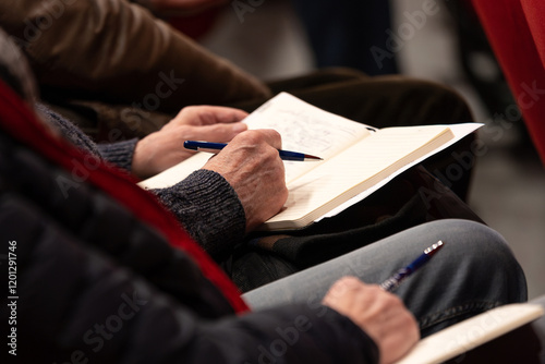 Détail des mains d'une personne écrivant sur un cahier pendant un séminaire
