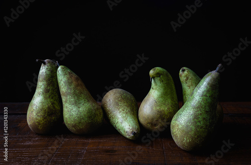 Six conference pears on a wooden table with dark background photo