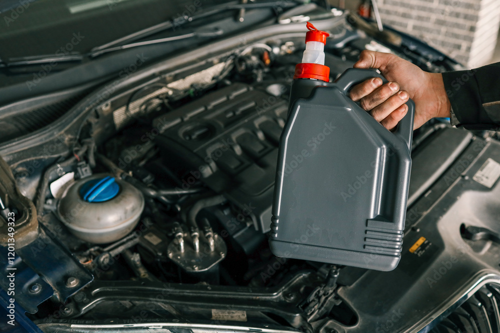 Close-up of a mechanic holding a bottle of motor oil and an oil dipstick, performing an oil change in a vehicle. Highlights car maintenance and servicing tasks Close-up of a mechanic holding a bottle of motor oil and an oil dipstick, performing an oil change in a vehicle. Highlights car maintenance and servicing tasks