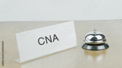 CNA Office or Room with Hand Ringing The Bell on Desk or Table Multiple Times.
