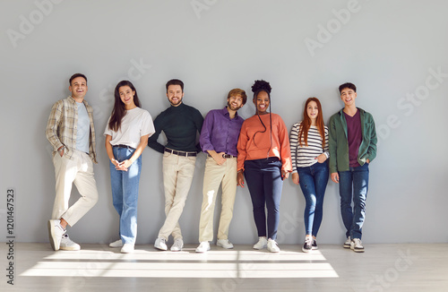 Obraz na plátně Group portrait of smiling young people standing near wall in looking into camera