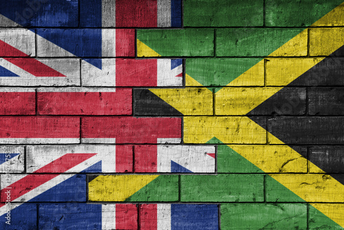 colourful painted big flag of great britain and flag of jamaica on a massive old brick wall background. concept photo