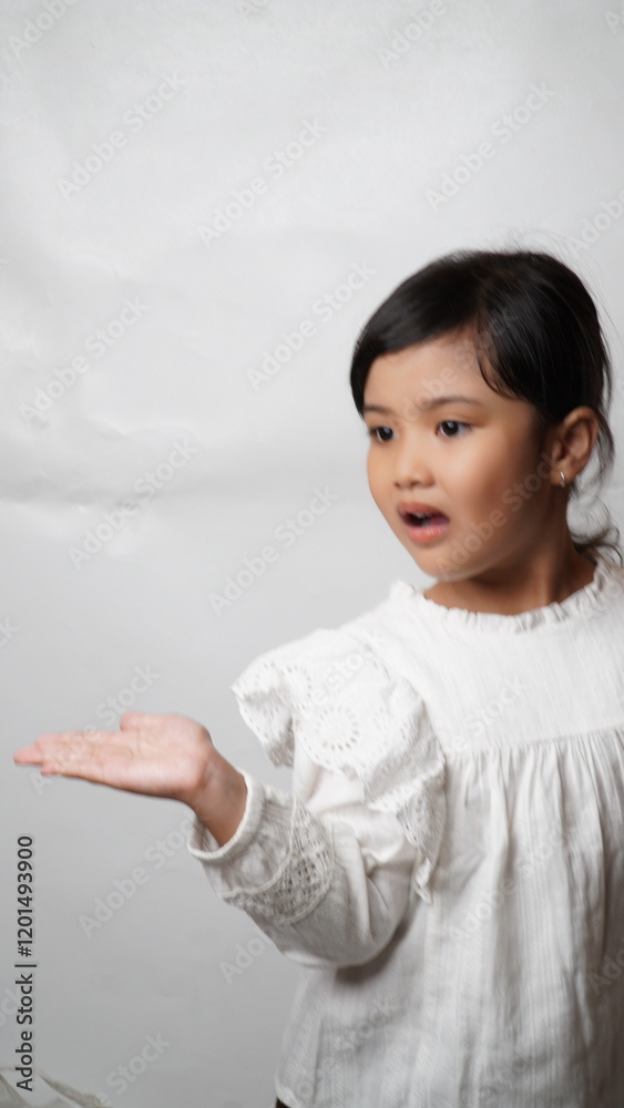Portrait an Asian girl wearing a white shirt and tied hair is smiling and standing with both palms raised facing upwards to the side pointing at something on a white background. Portrait an Asian girl wearing a white shirt and tied hair is smiling and standing with both palms raised facing upwards to the side pointing at something on a white background.