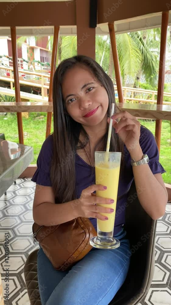 young asian woman drinking mango shake cocktail at a bar in the tropics young asian woman drinking mango shake cocktail at a bar in the tropics