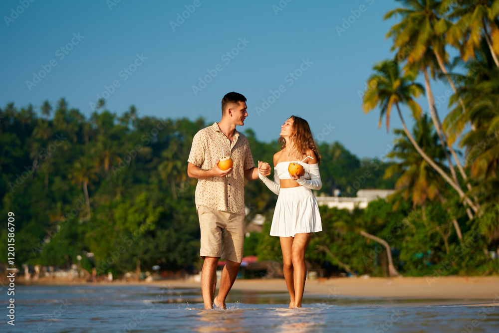 Couple stroll barefoot on sandy beach, holding coconuts, sipping drinks, enjoying sunset. Casual date, tropical vacation vibe. Smiles, flirty conversation, ocean backdrop, intimate walk together. Couple stroll barefoot on sandy beach, holding coconuts, sipping drinks, enjoying sunset. Casual date, tropical vacation vibe. Smiles, flirty conversation, ocean backdrop, intimate walk together.