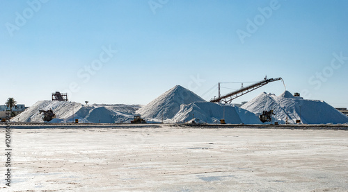 Foto Landscape with desert salt mining factory with piles of white mineral and industrial equipment