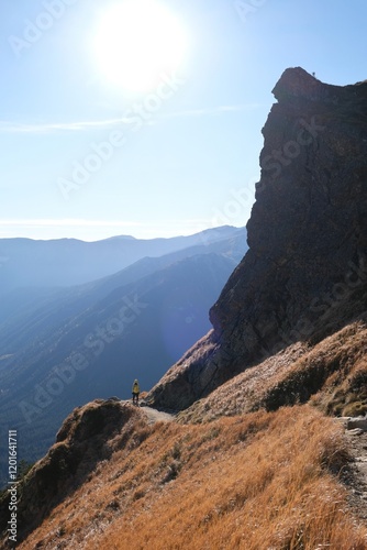 Scenery of autumn Tatras Mountains with very little silhouette of hiking person on trail. Czerwone Wierchy range from around Kasprowy Wierch Peak, Tatras Mountains, Poland.   photo