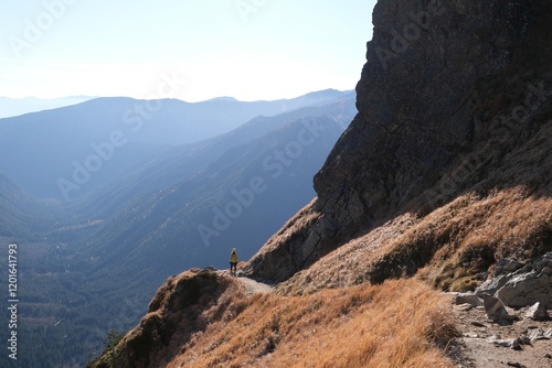 Scenery of autumn Tatras Mountains with very little silhouette of hiking person on trail. Czerwone Wierchy range from around Kasprowy Wierch Peak, Tatras Mountains, Poland.  