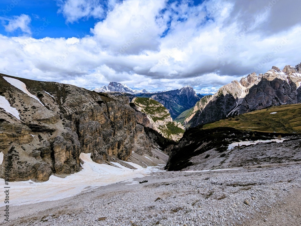 Fototapeta premium Panoramic alpine valley with snow-covered slopes and limestone peaks in the Dolomites, Italy