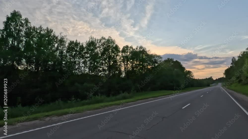 View from the car window, passage against the background of sunset, sun rays and glare through trees and houses View from the car window, passage against the background of sunset, sun rays and glare through trees and houses