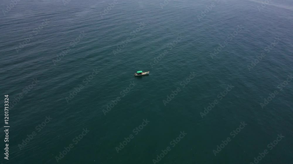 High-altitude aerial drone shot capturing the serenity of a lone fisher boat in the middle of the deep blue sea.