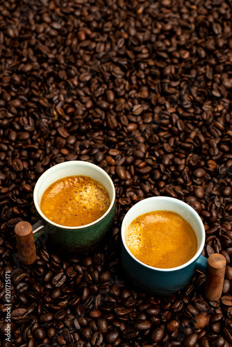 Two cups of espresso sitting in coffee beans 