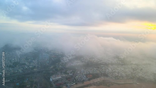 Immersive aerial drone shot of Vijayawada city during sunrise, with a bird’s-eye view above the clouds. photo